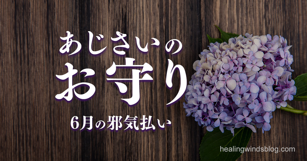 木目調の背景に優しく咲く薄紫のあじさいの花。「あじさいのお守り」「6月の邪気払い」という文字が中央に配置され、梅雨の季節に込められた祈りや浄化の意味を伝える静かな印象のアイキャッチ画像。