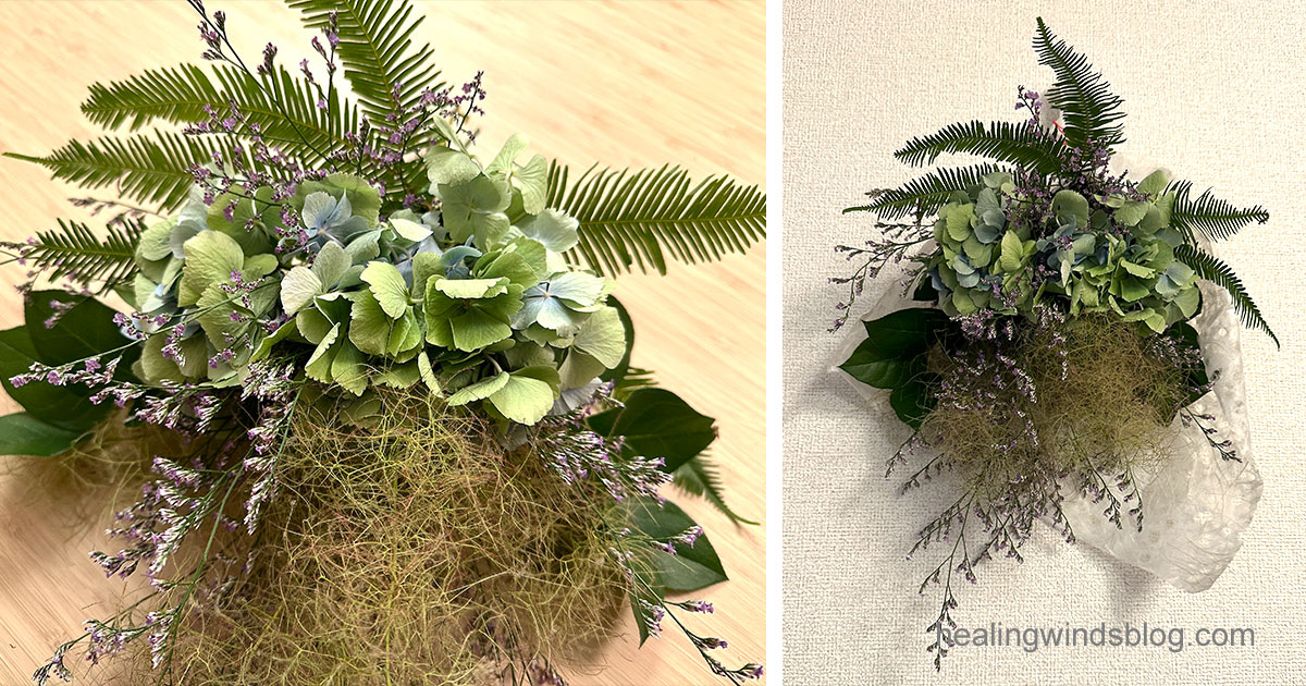 手作りの紫陽花守り。左側は机の上に置いた完成直後の状態で、グリーンと紫の草花がふんわりと広がっている。右側は壁に吊るして飾った様子で、白い和紙に包まれた飾りが整った印象を与える。