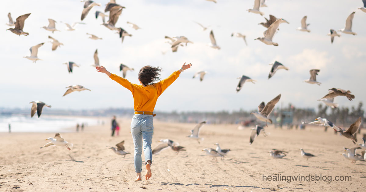 自由を感じるビーチで、鳥たちの間を駆け抜ける女性の解放感あふれるシーン